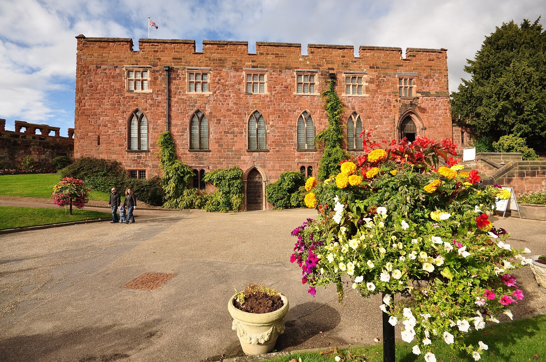 Red-sandstone façade of Shrewsbury Castle with flowers in the foreground